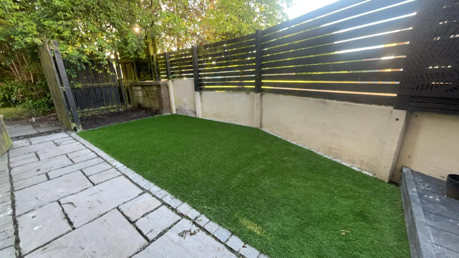 Artificial grass lawn with paved edging and slatted fence panels in Kilwinning.