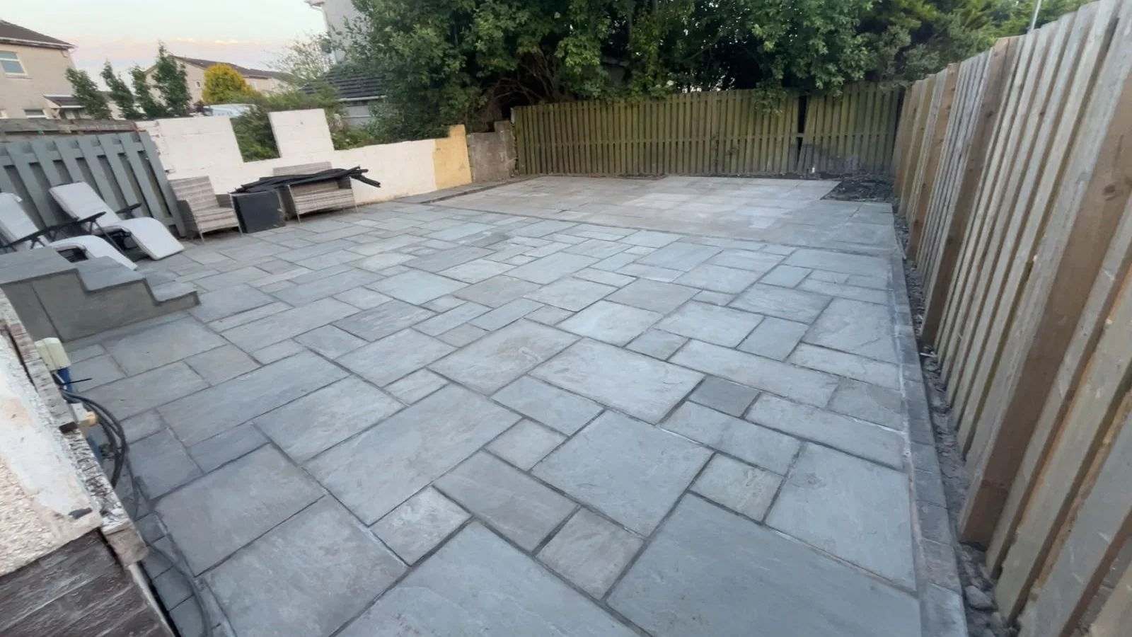 Wide Indian sandstone patio beside timber fencing in Kilwinning.
