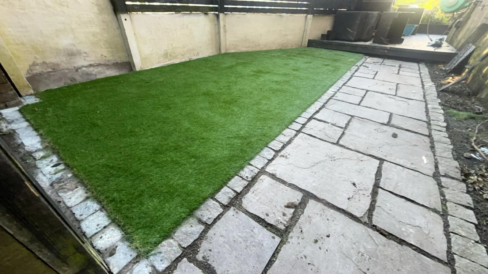 Artificial grass lawn alongside a paved path in a Kilwinning garden.