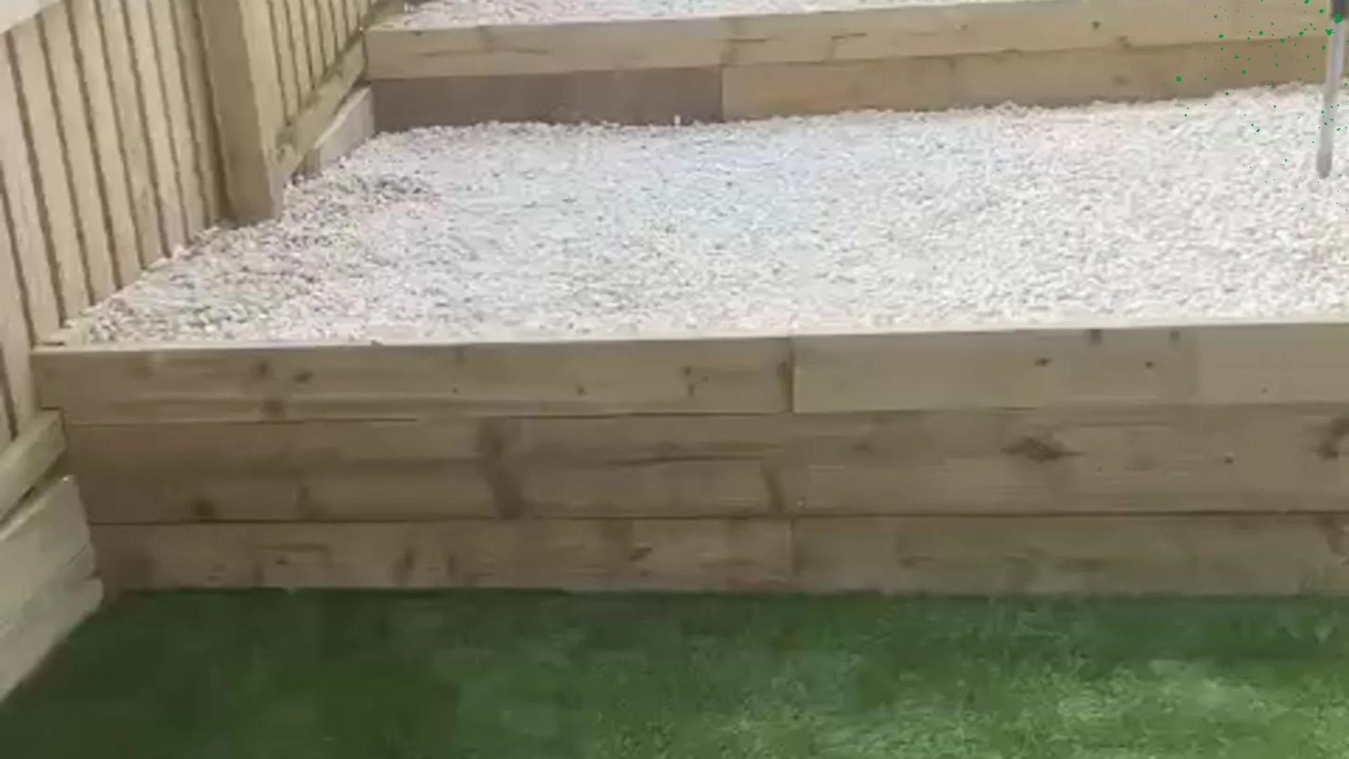 Retaining sleeper walls built by Jackson's, finished with stone chips and artificial turf — the timber fencing alongside was not part of the job.