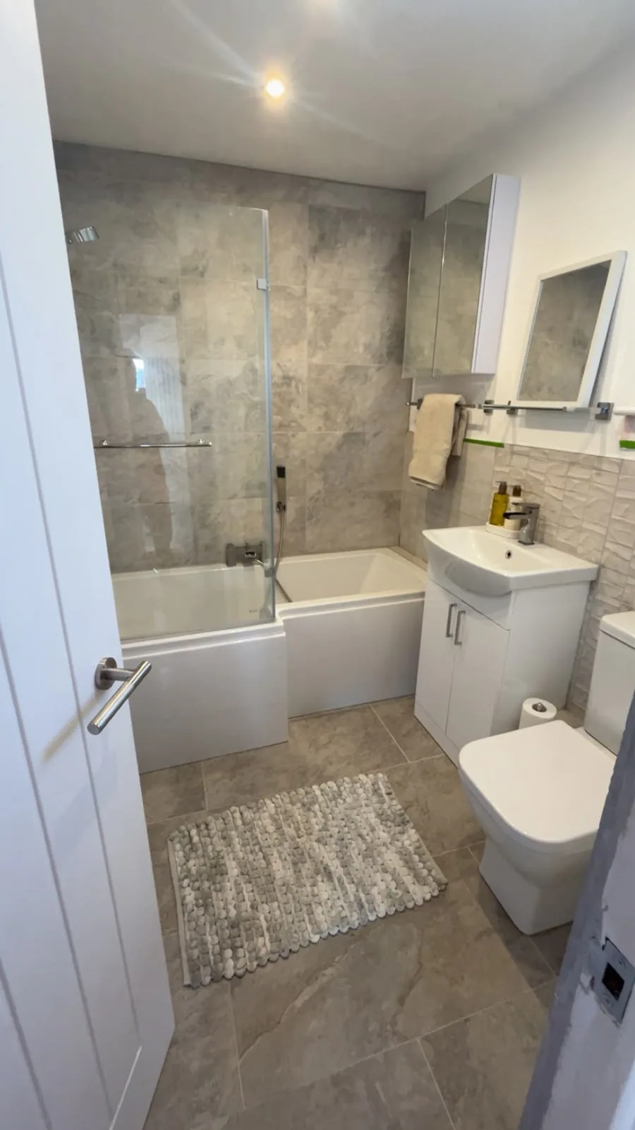 Newly tiled bathroom walls with a tiled bath surround and finished grout lines.