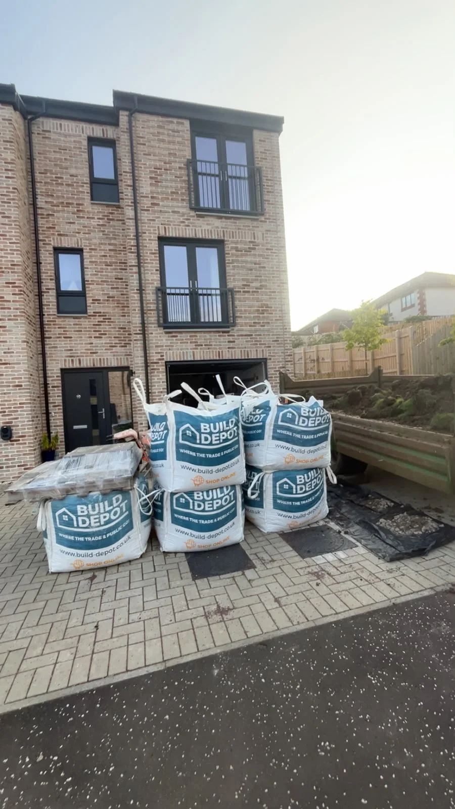 Materials bags on a block-paved driveway beside a Greenock townhouse.