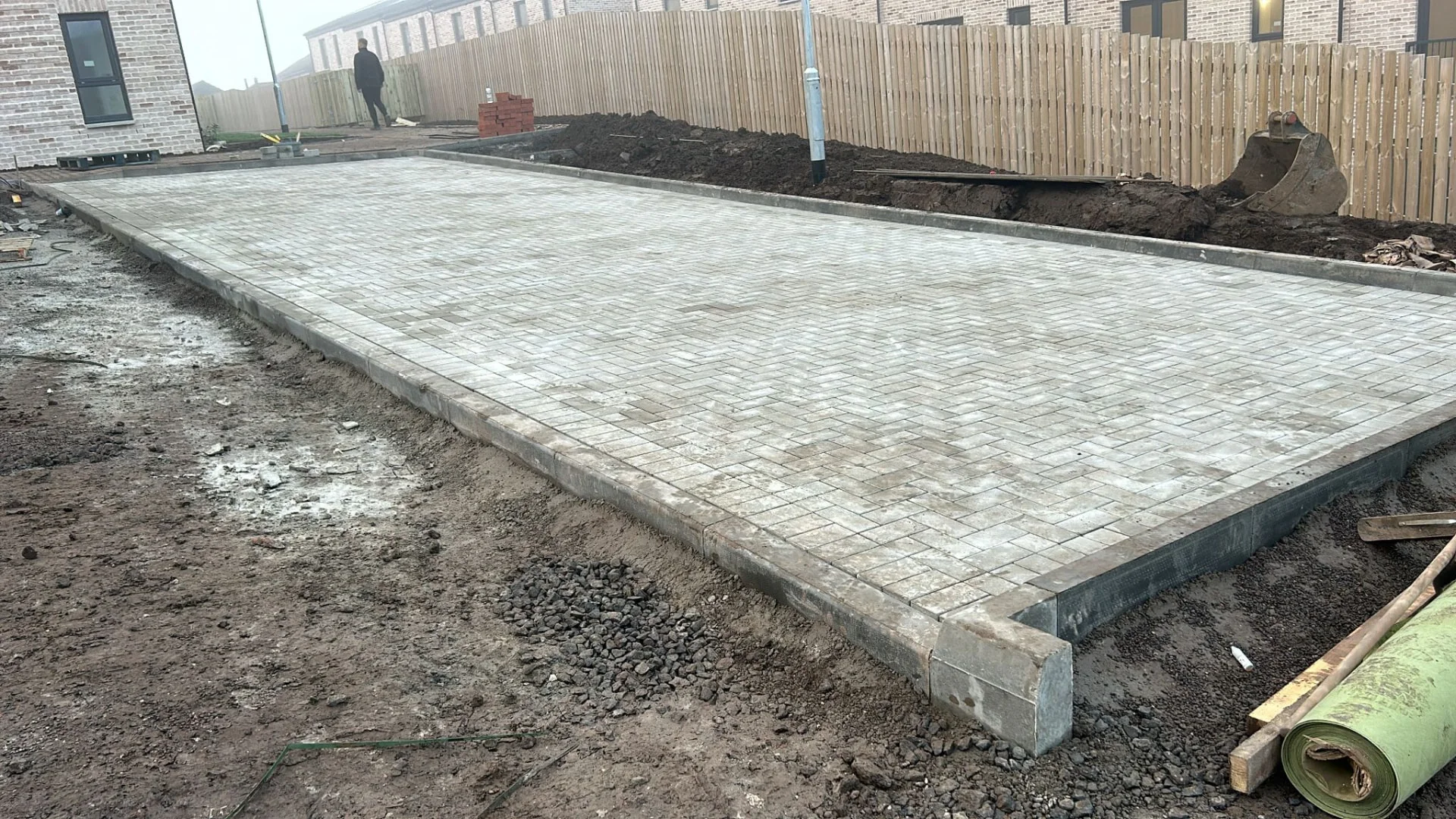 Freshly laid monoblock car park with kerb edging at the Greenock luxury townhouse development, groundworks still under way around it.