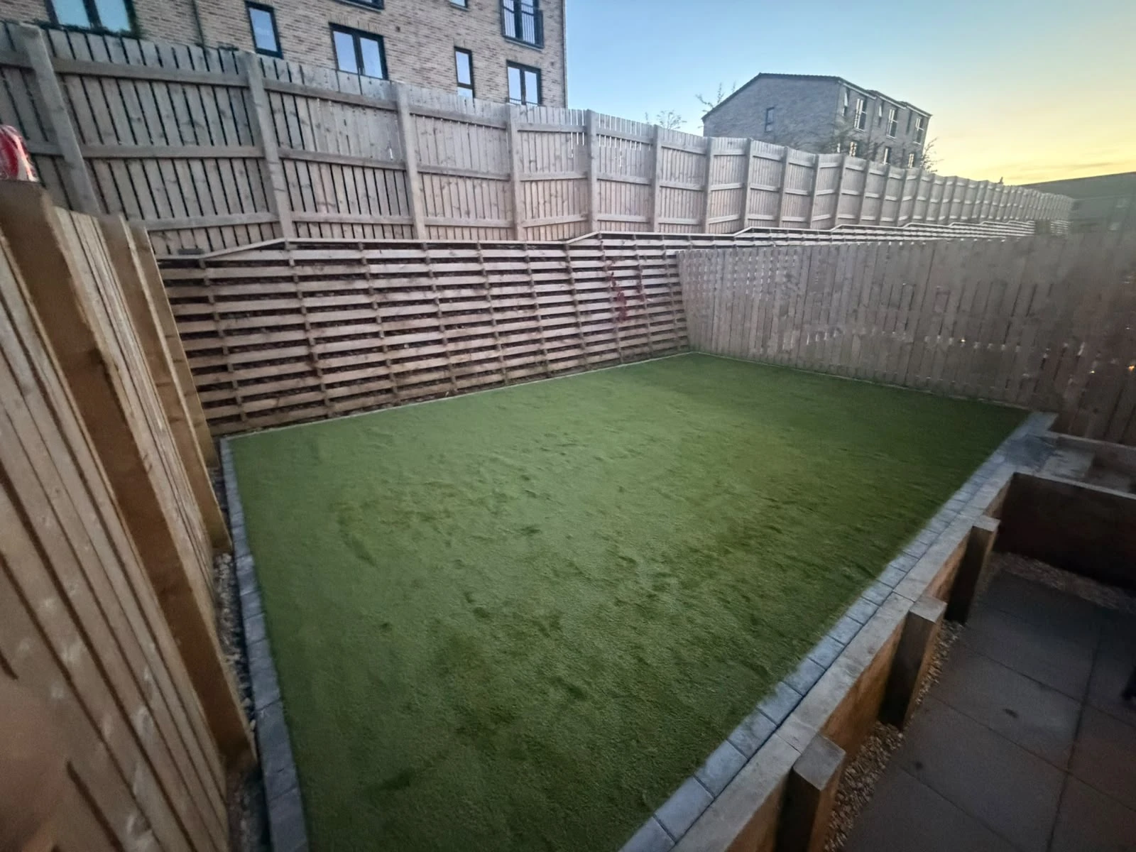 Finished artificial grass lawn with block edging and sleeper retaining walls at the Greenock luxury townhouses.