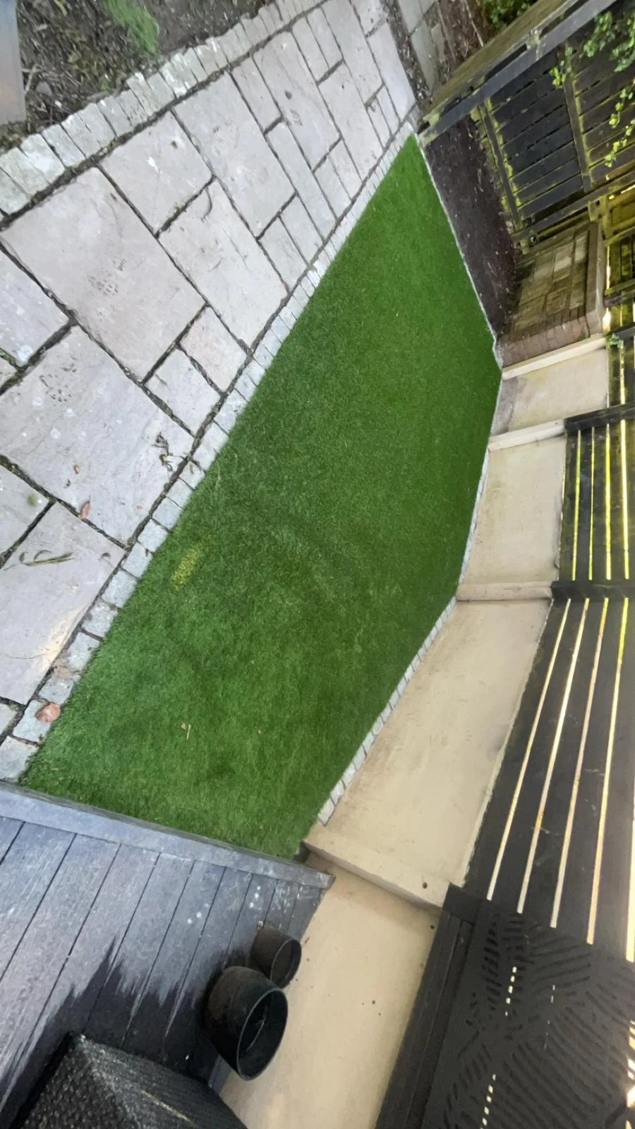 Artificial grass beside paving and decking in a Kilwinning garden.