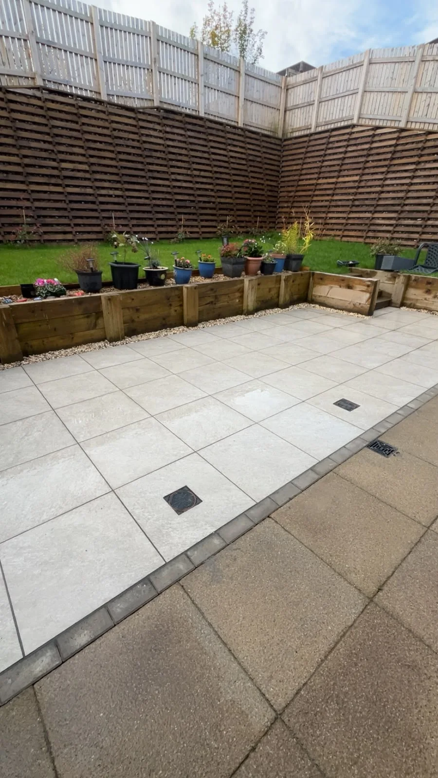Paved Greenock townhouse garden with timber fencing and potted plants.