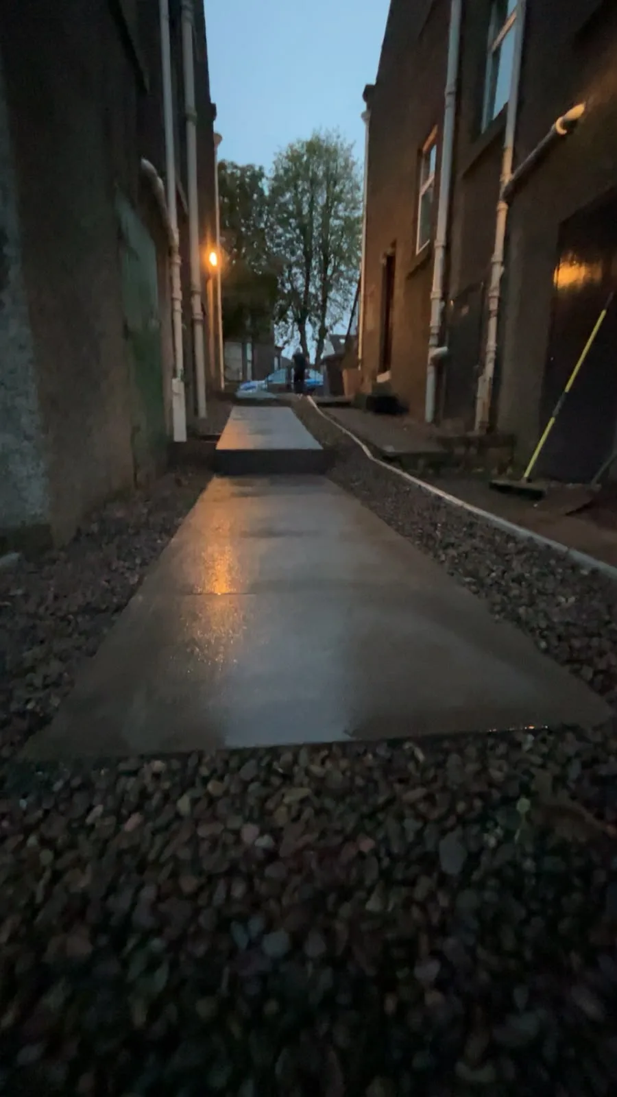 Paving slabs and steps forming a side return path to the side door of a house, photographed at dusk.