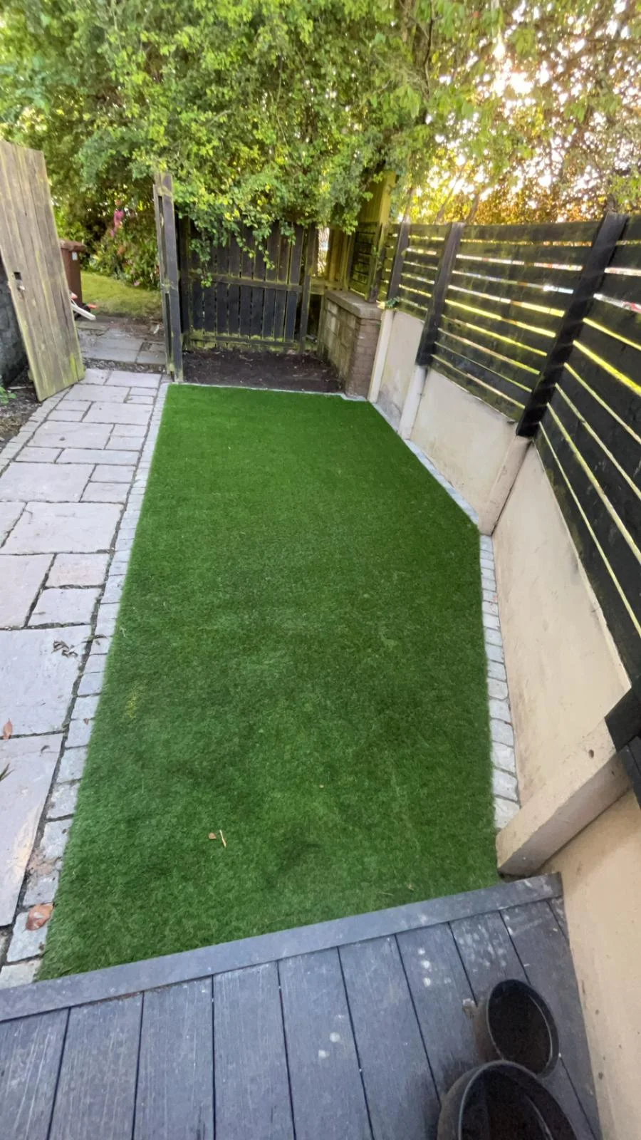 Artificial grass lawn between a paved path and decking in Kilwinning.