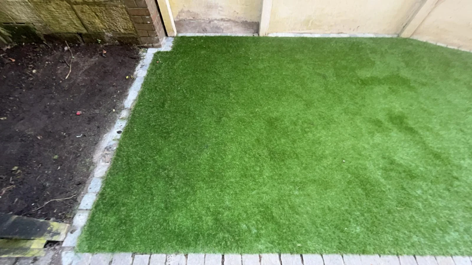 Newly laid artificial grass edged with stone setts in Kilwinning.