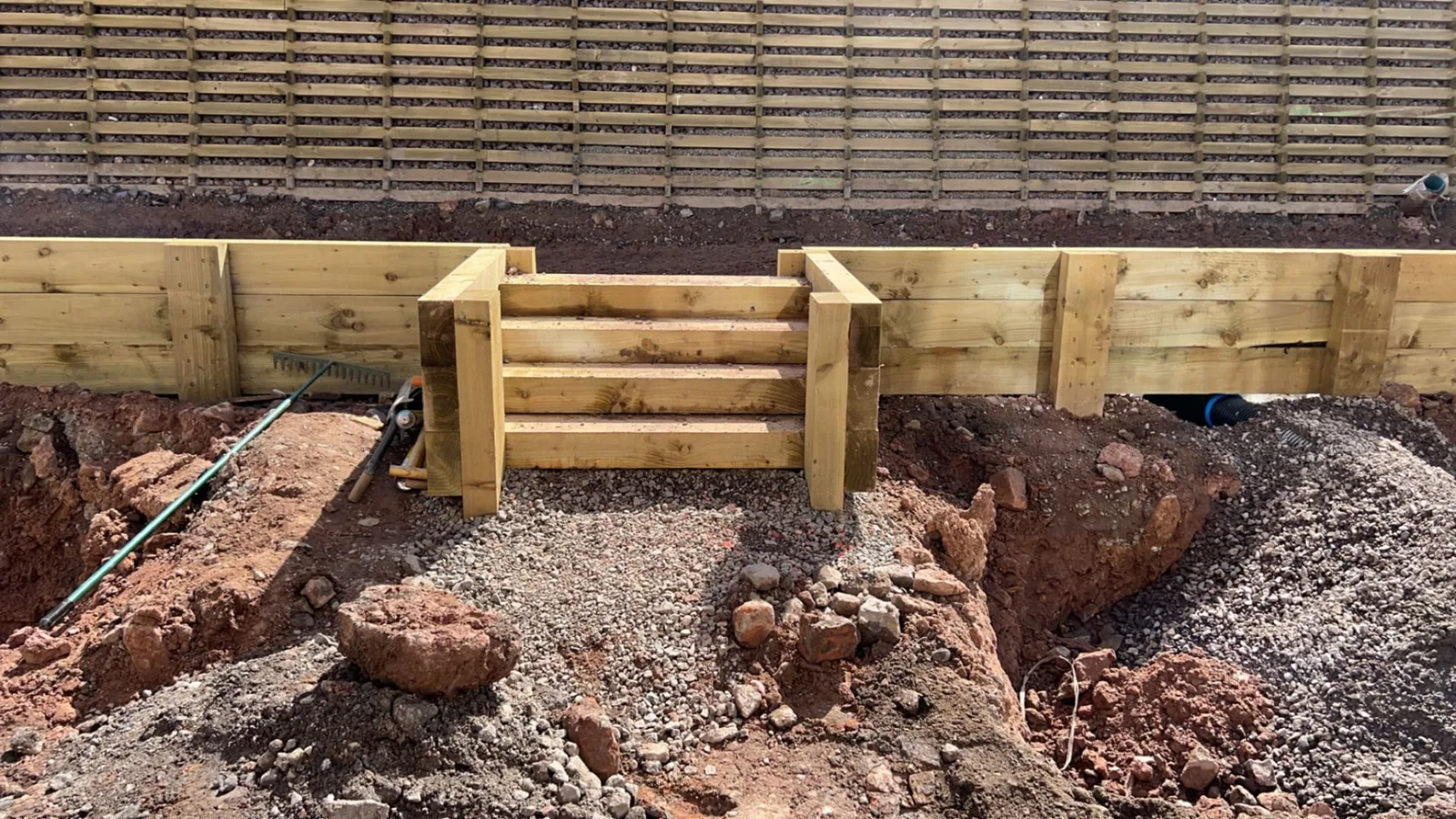 Sleeper steps and retaining wall built by Jackson's under construction in a garden, set into freshly excavated ground — the timber fencing behind was not part of the job.