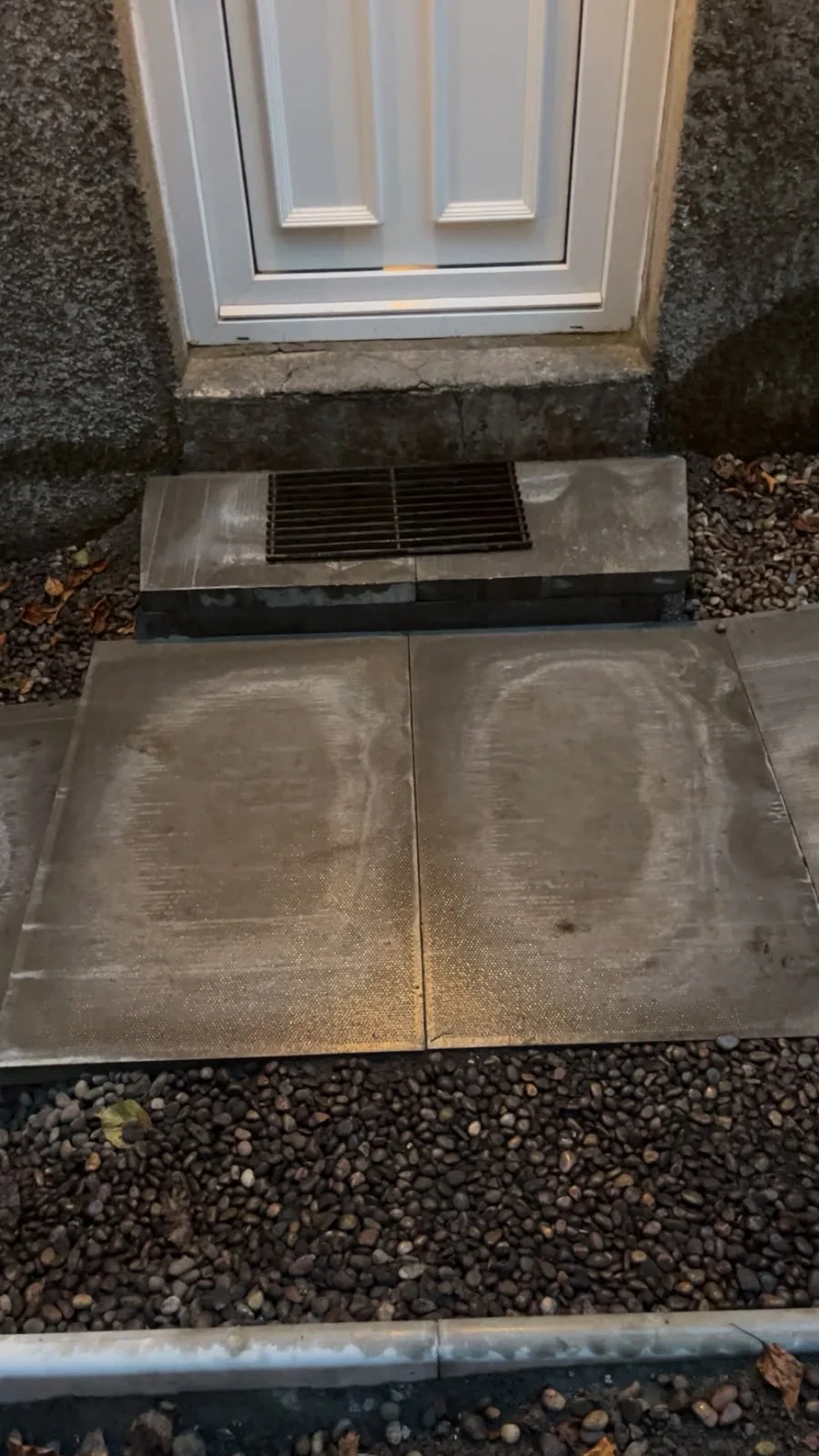 Slabbed doorstep with a drainage grate at a Greenock back door.