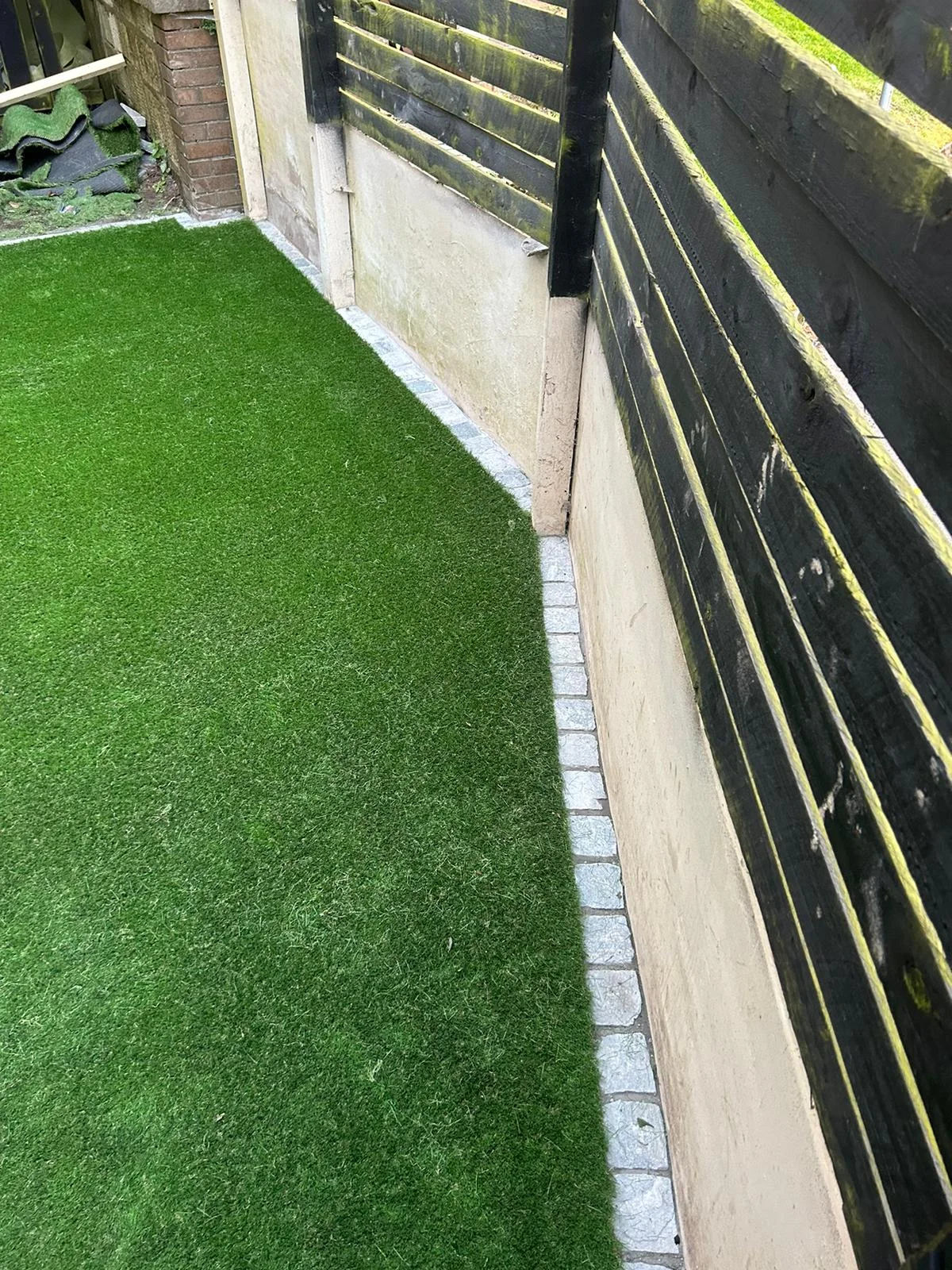 Artificial grass laid along a fenced boundary in Kilwinning.